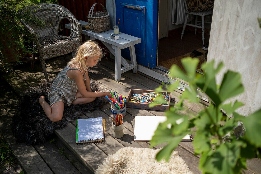 Mädchen malt vor einem Holzferienhaus