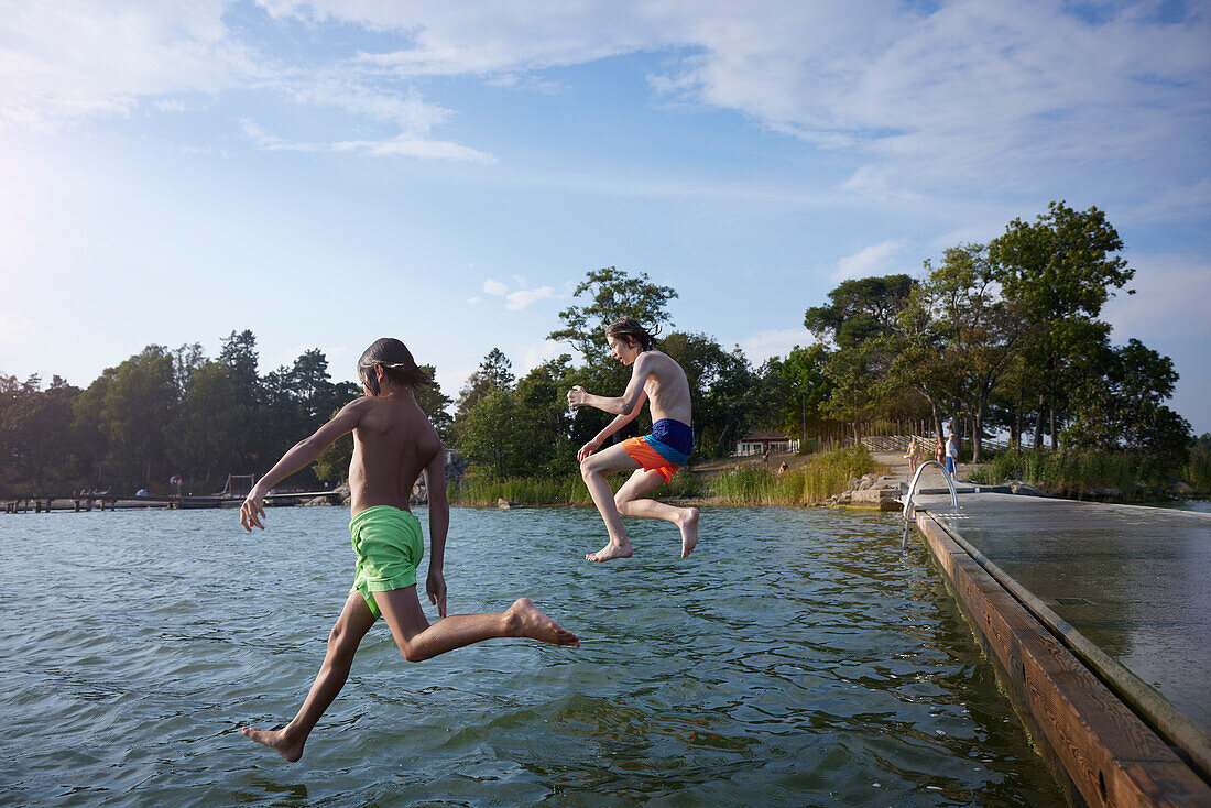 Jungen, die ins Wasser springen
