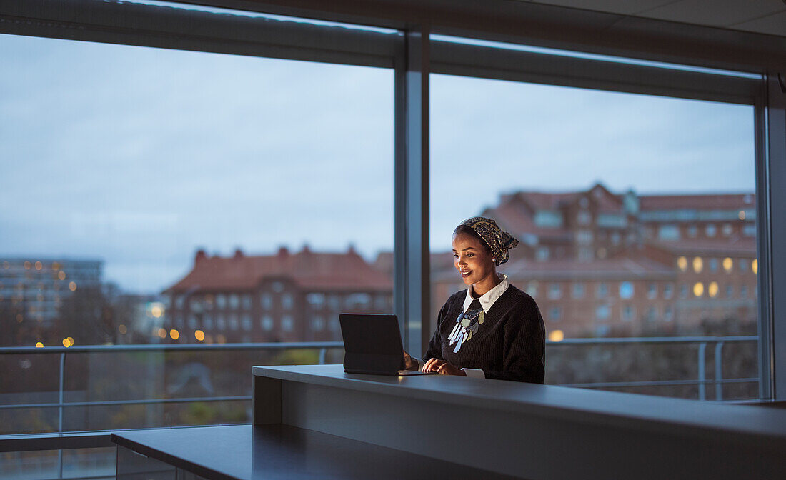 Lächelnde junge Frau bei der Arbeit an einem Laptop