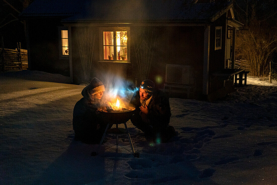 Mann und Frau zünden im Winter den Grill an