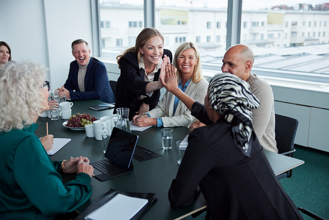 Women giving each other high five at business meeting