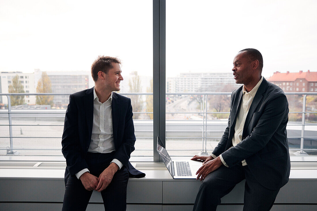 Businessmen sitting by window and talking