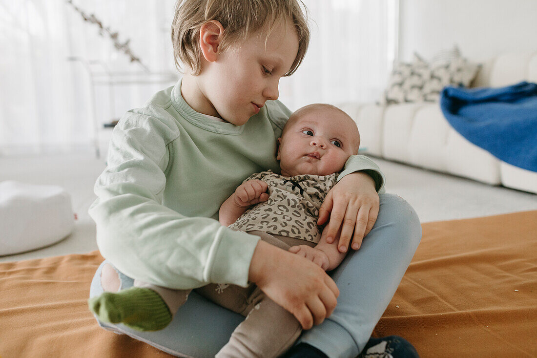 Junge sitzend mit Babygeschwisterchen