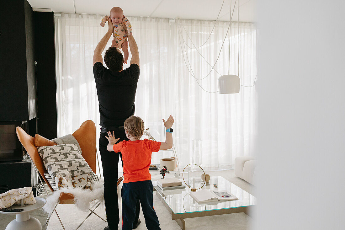Father playing with children in living room