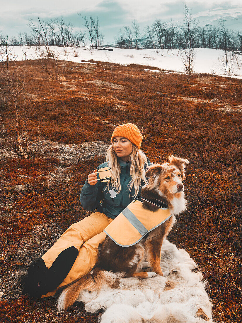 Frau sitzt mit Hund im Winter