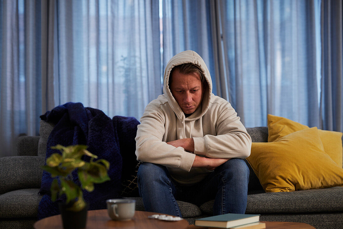 Ill man sitting on sofa