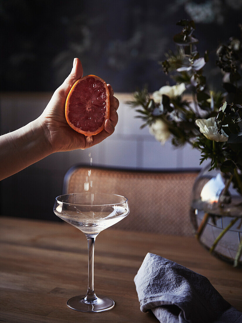 Hand squeezing orange into martini glass