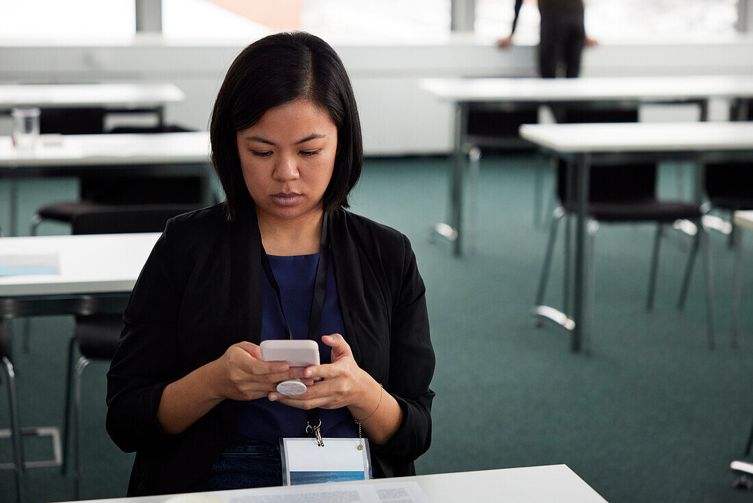 Businesswoman sitting at desk and using smart phone