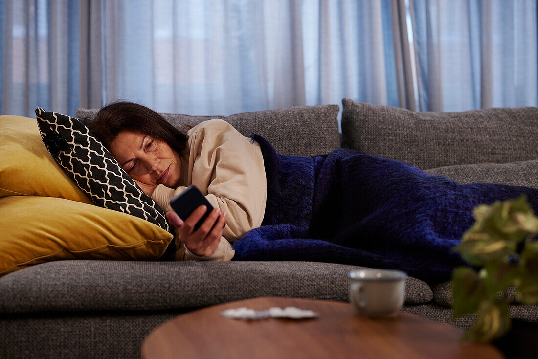 Frau auf dem Sofa telefoniert mit Handy