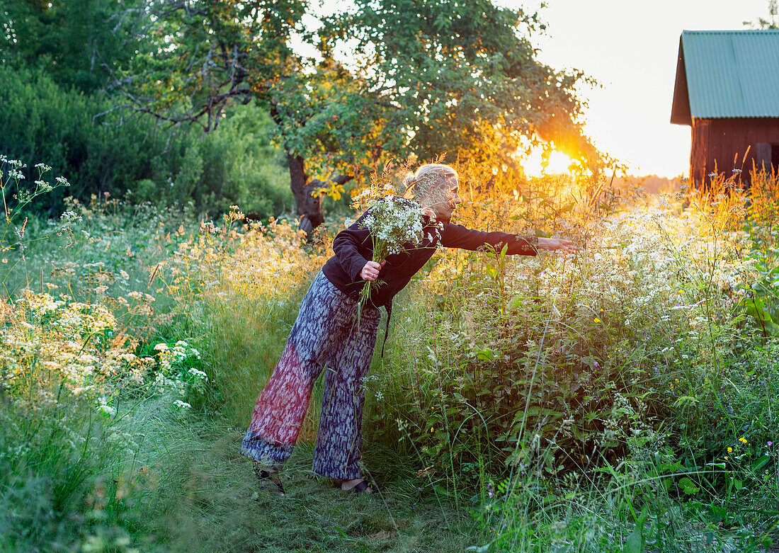 Lächelnde Frau beim Pflücken von Wildblumen