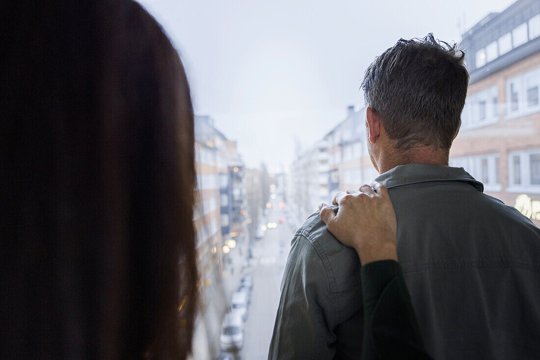 Frau berührt den Arm eines Mannes am Fenster