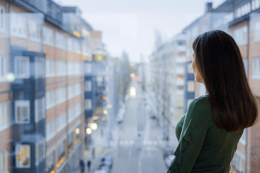 Frau blickt aus dem Fenster auf die Straße