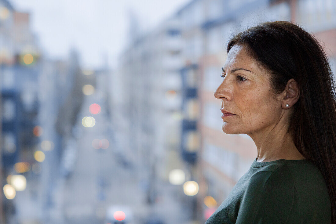 Profilansicht einer reifen Frau, die neben einem Fenster steht