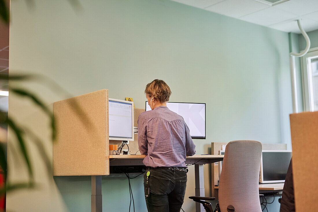 Rückansicht einer Frau, die einen Computer im Büro benutzt