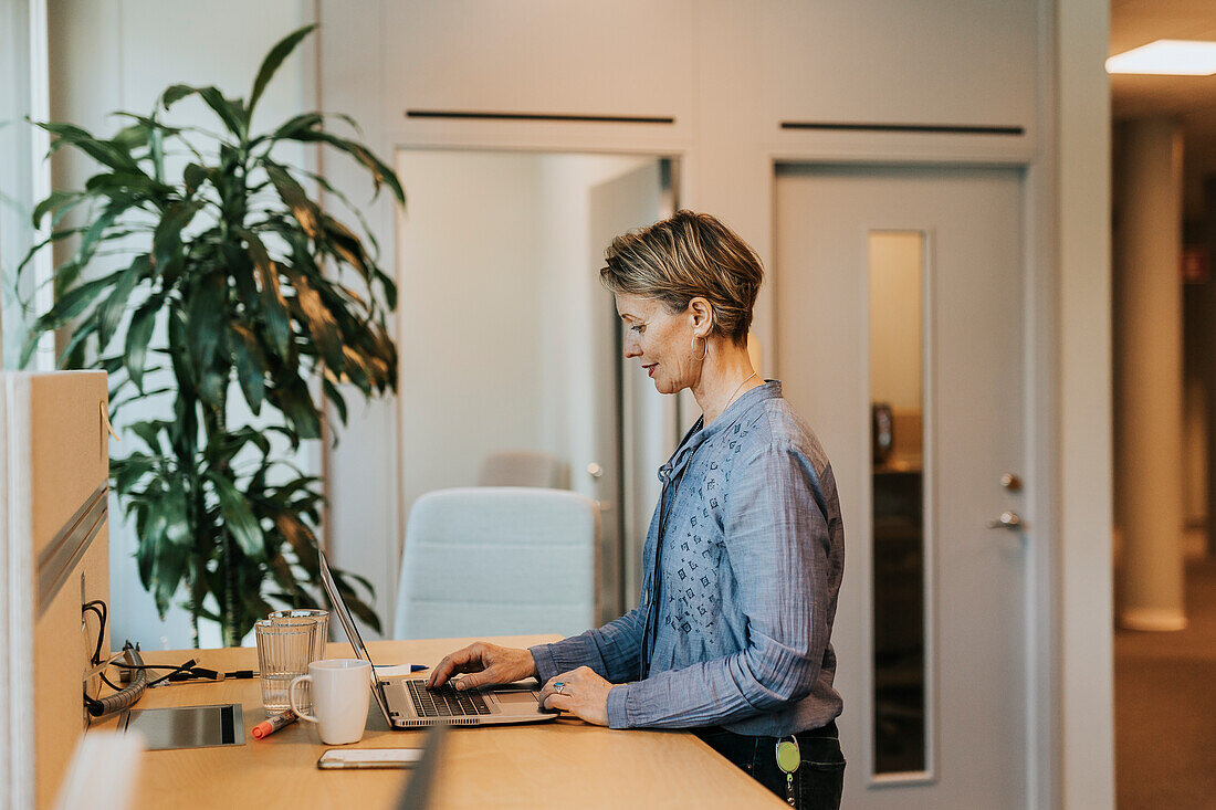 Smiling woman using laptop in office