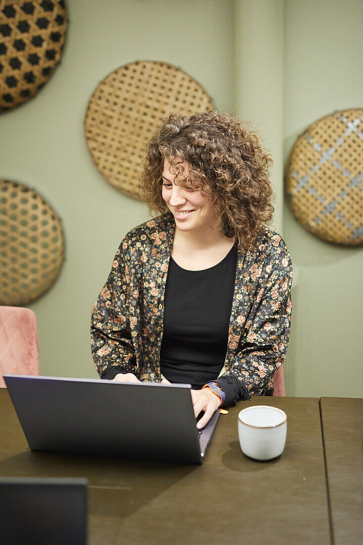 Smiling woman using laptop at work