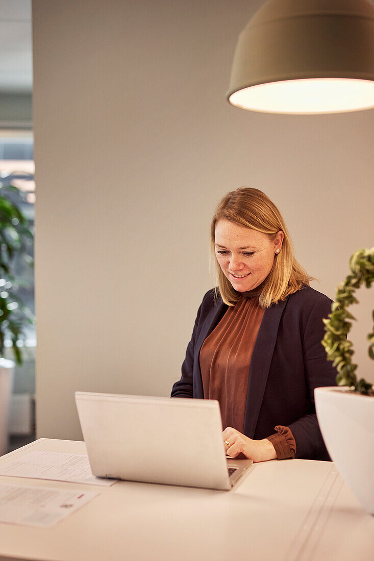 Lächelnde Frau benutzt Laptop im Büro