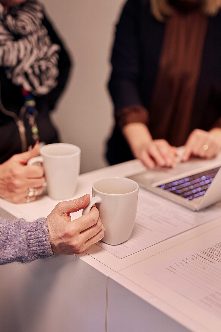 Frauenhände halten Becher im Büro