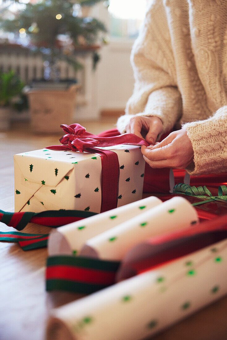 Person packt Weihnachtsgeschenke zu Hause ein