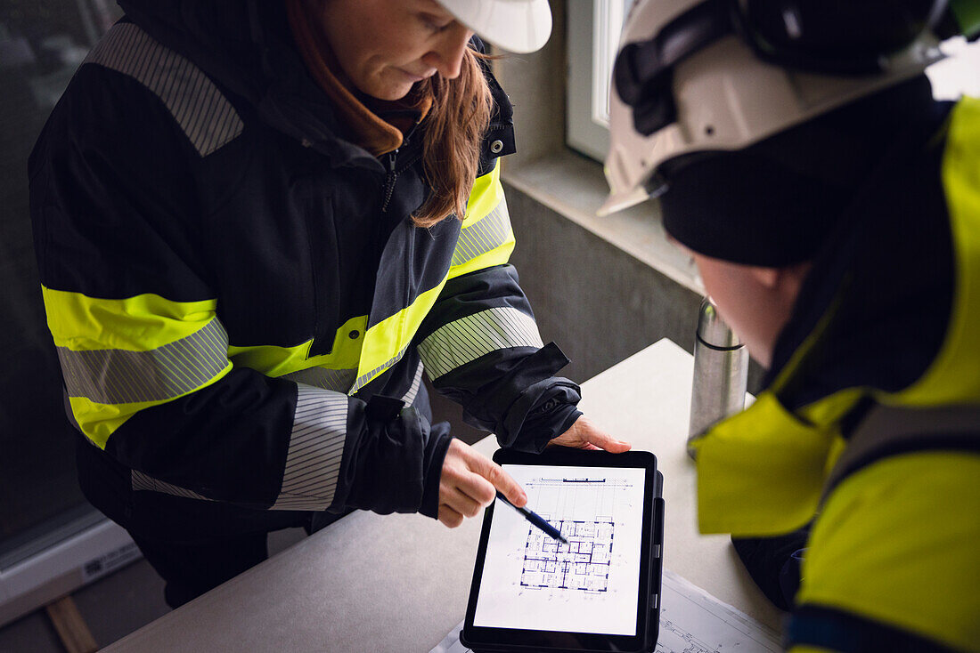 Engineers checking plans on digital tablet
