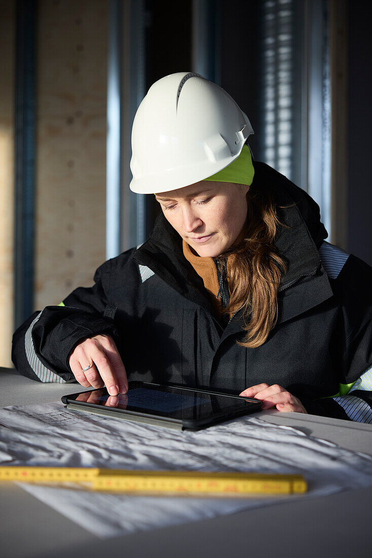 Female engineer checking plans on digital tablet