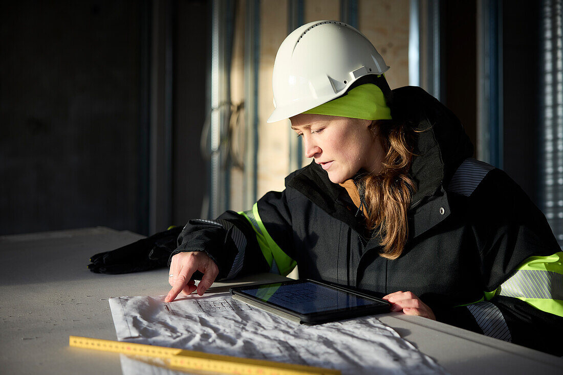 Female engineer checking plans on digital tablet