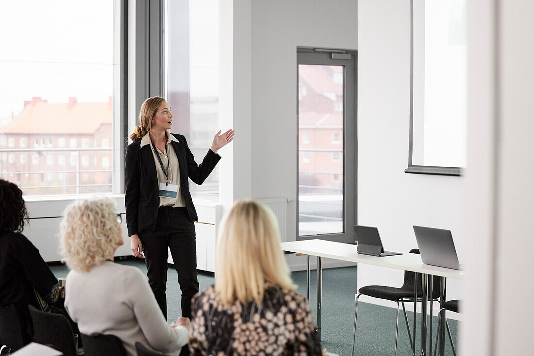 Business people sitting and listening to businesswoman