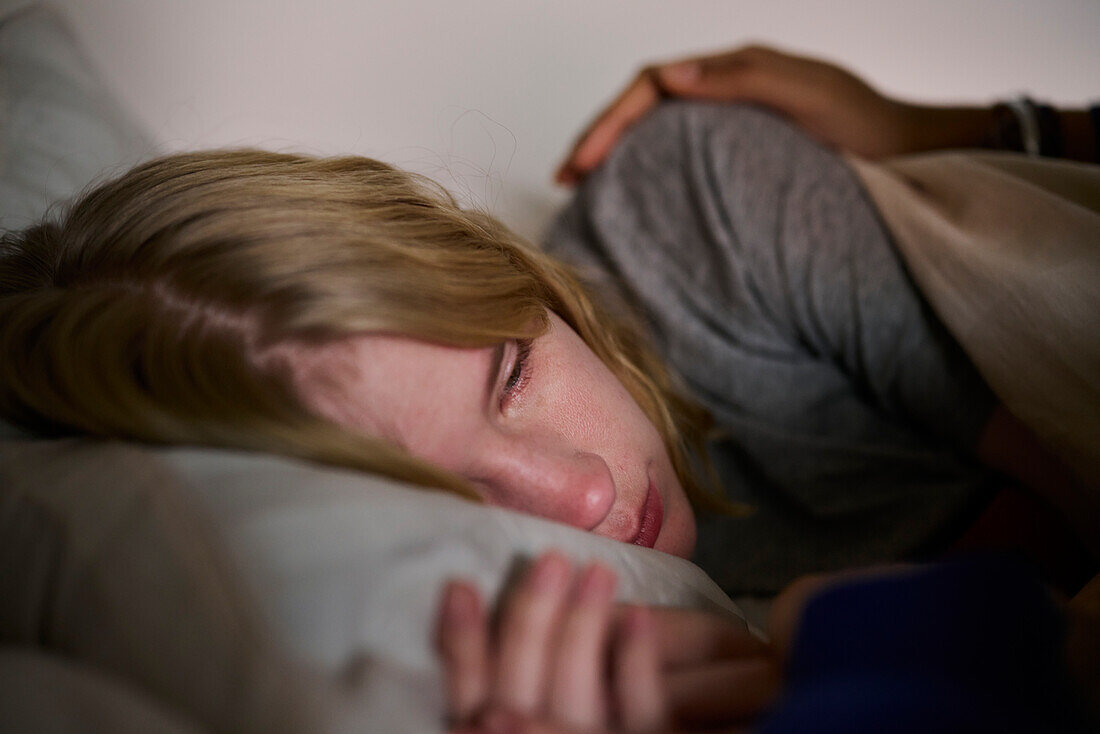 Weinende junge Frau im Bett liegend