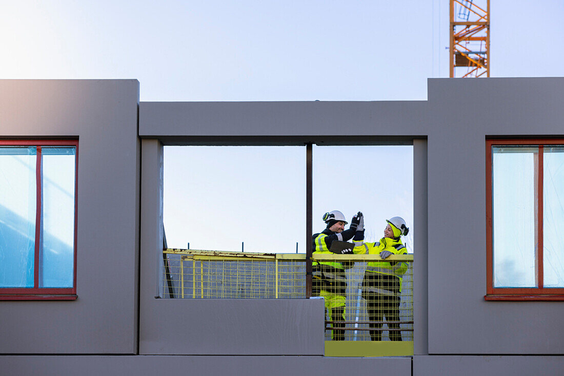 Two engineers high fiving at construction site