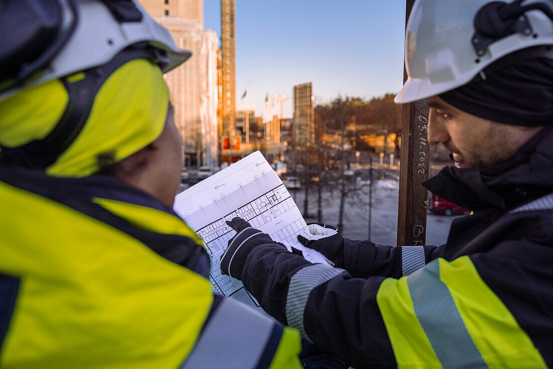 Two engineers looking at blueprints at construction site