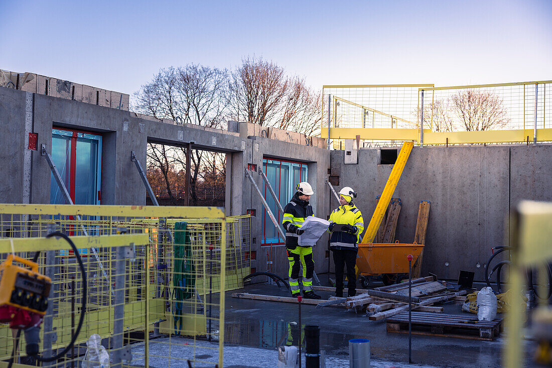 Two engineers looking at blueprints at construction site