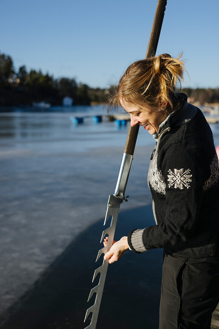 Smiling woman at lake using ice saw