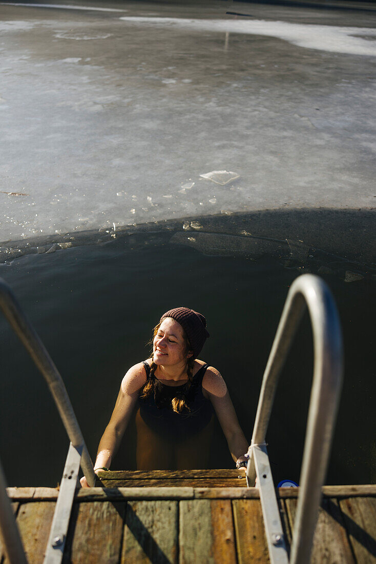 Frau schwimmt im Winter in einem See