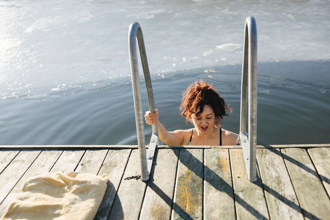 Frau schwimmt im Winter in einem See