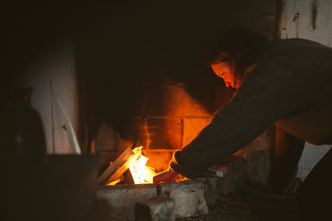 Woman preparing firewood in fireplace