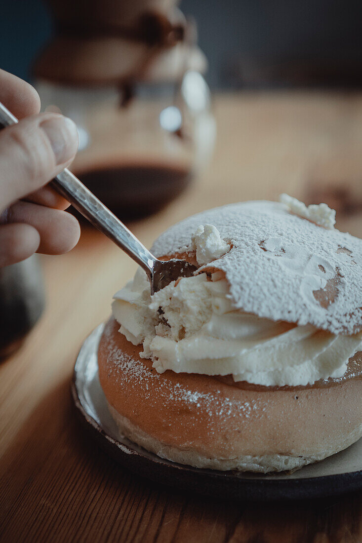 Person isst traditionelles Semla-Brötchen