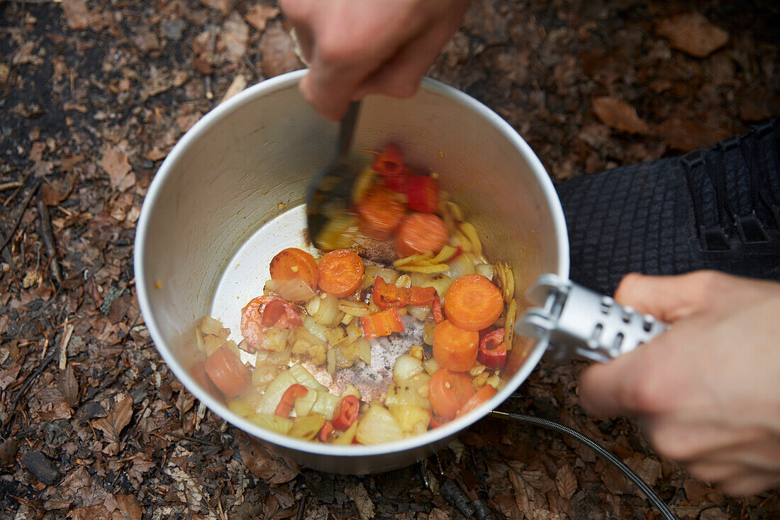 Männerhände beim Zubereiten von Essen im Freien