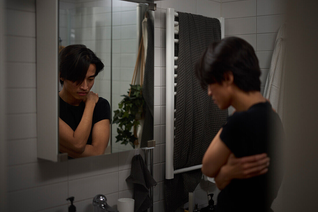 Junger Mann schaut in den Spiegel