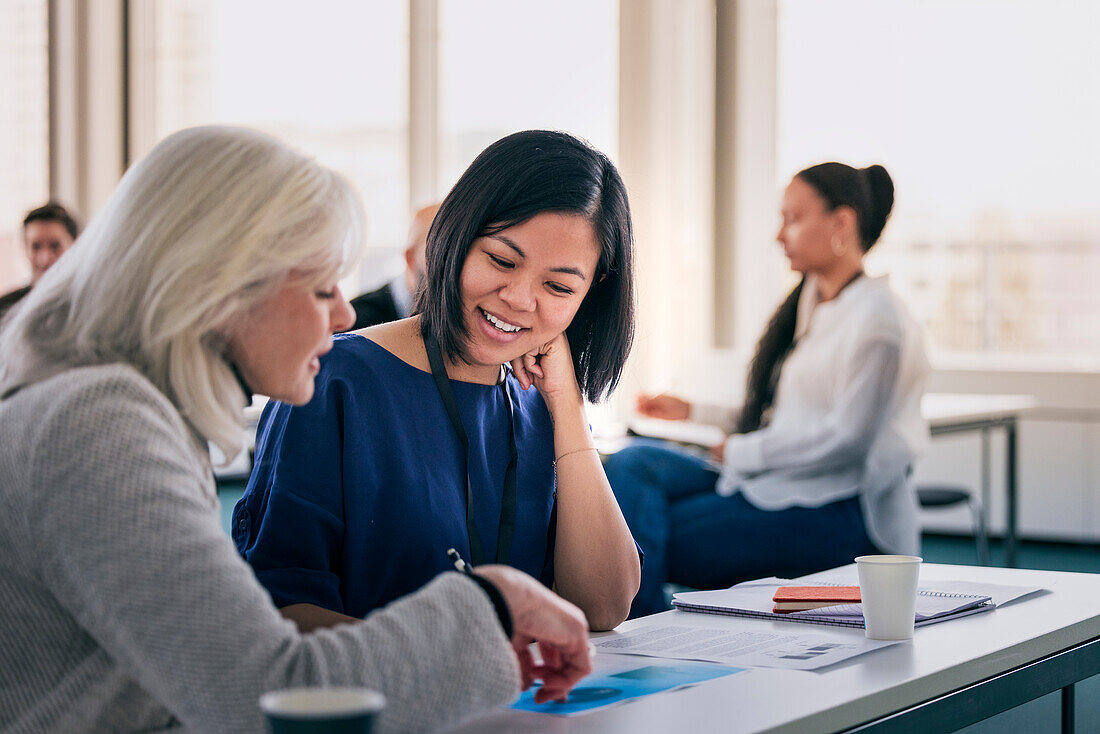 Lächelnde Frauen, die zusammen in der Klasse sitzen