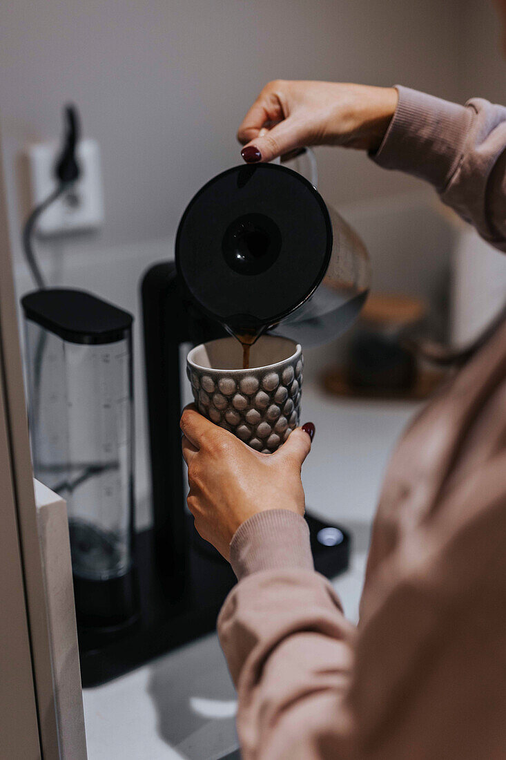 Frauenhände gießen Kaffee in Tasse