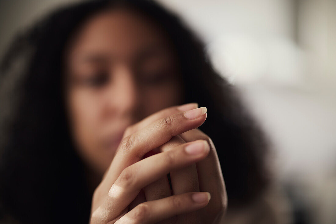 Pensive young woman picking at nails