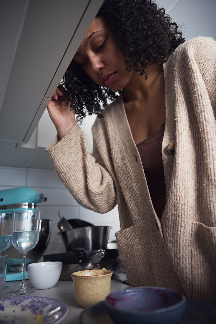 Pensive young woman standing in kitchen