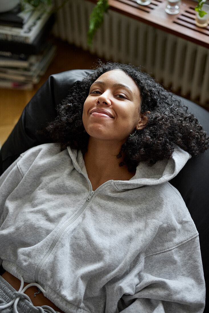 Porträt einer lächelnden jungen Frau auf einem Sitzsack liegend