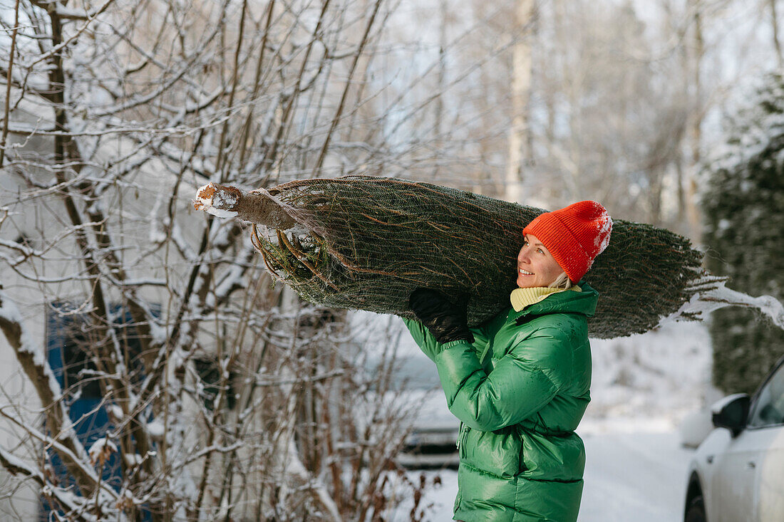 Smiling woman carrying Christmas tree