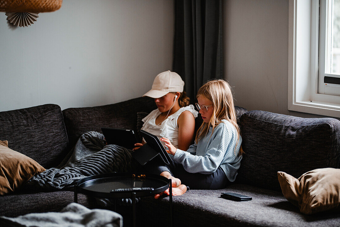 Girls on sofa using digital tablets