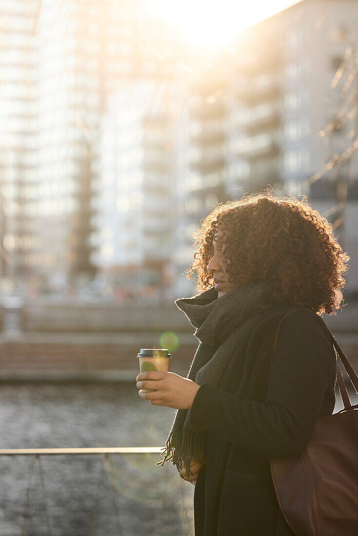 Schöne Frau mit Kaffee zum Mitnehmen beim Spaziergang in der Stadt