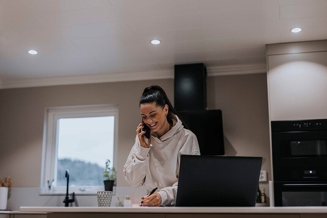 Woman in kitchen talking via cell phone