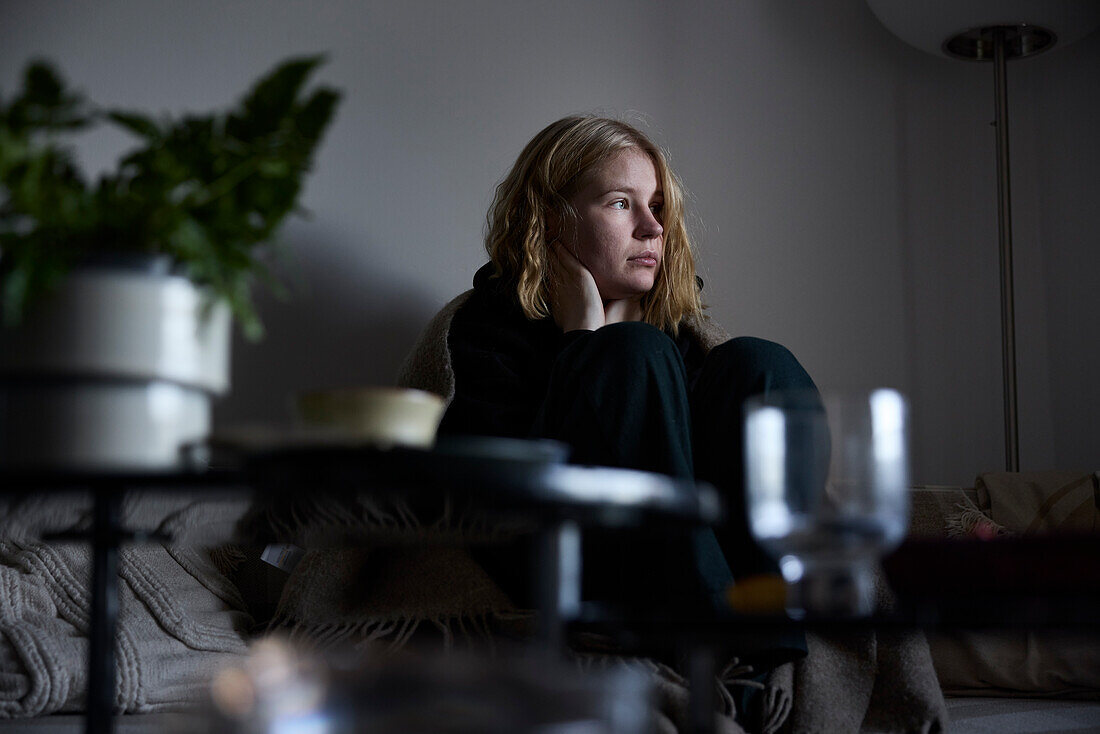 Pensive teenage girl sitting on sofa