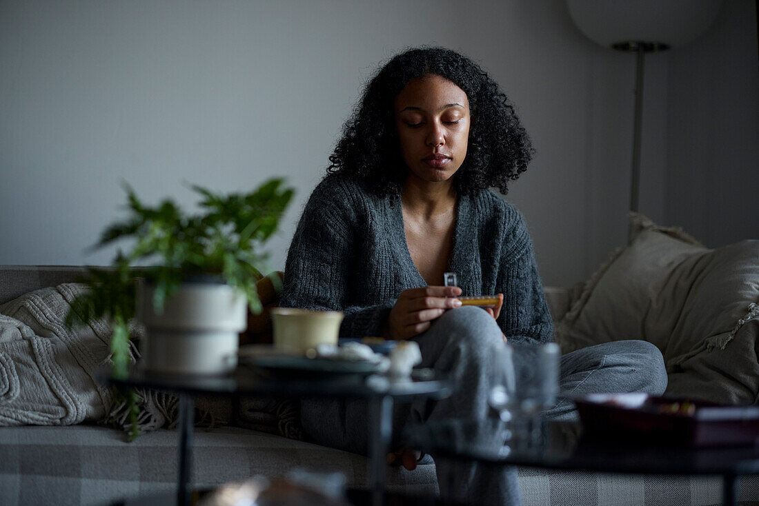 Pensive young woman holding pill box