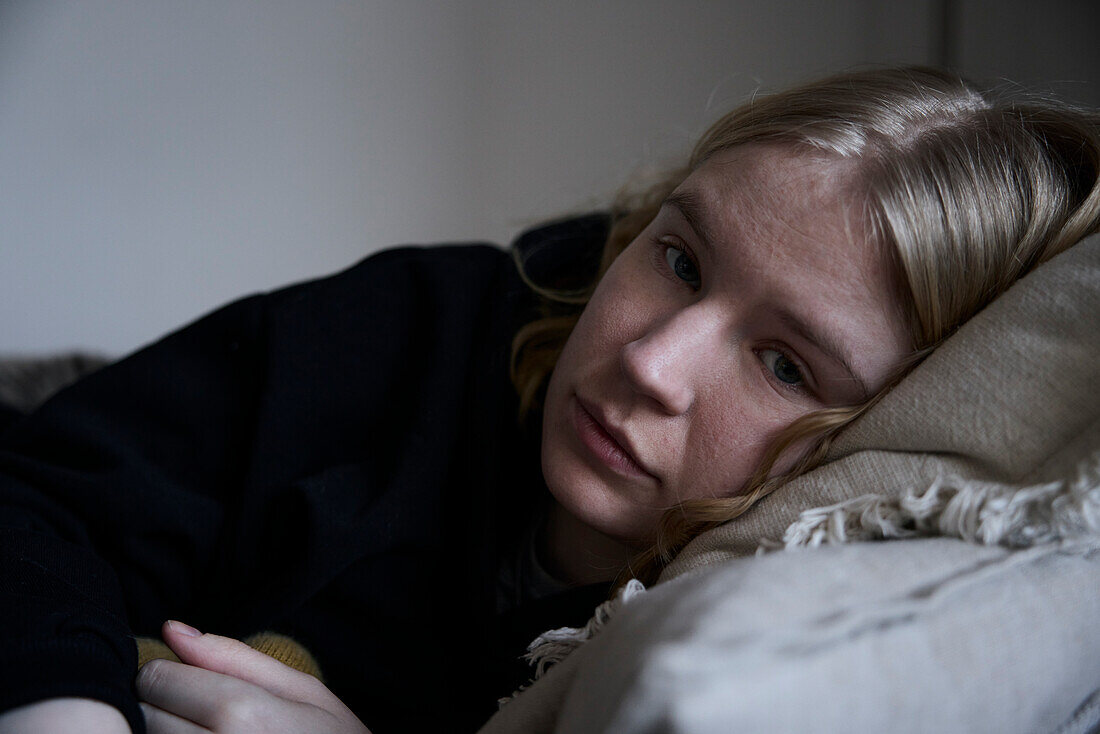 Portrait of pensive teenage girl lying in bed